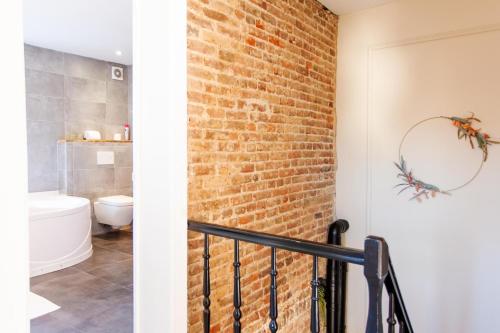 a brick wall in a bathroom with a toilet at Stijlvolle @ luxe vrijstaande woning Maastricht in Eijsden