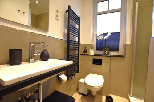 baño con lavabo y aseo y ventana en FeWo 1 "Birkenast" 1OG inkl Strandkorb, en Dahme