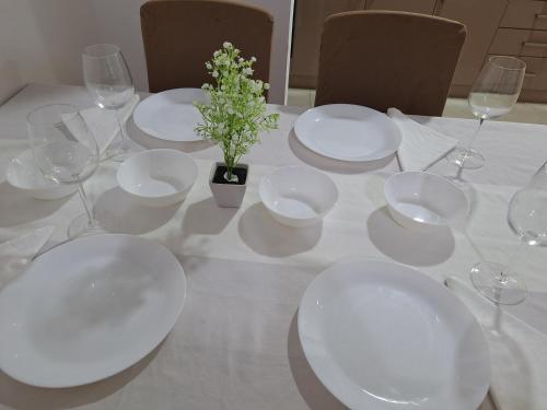 a table with white plates and glasses and a plant at RIVIJERA CITY in Belgrade
