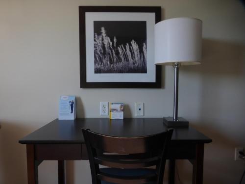 a desk with a lamp and a chair in a room at Super 8 by Wyndham Peterborough in Peterborough