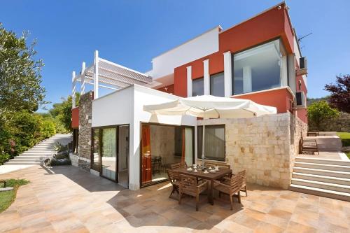 uma casa com um pátio com uma mesa e um guarda-chuva em Villa Iside Luxury Stay em Conversano