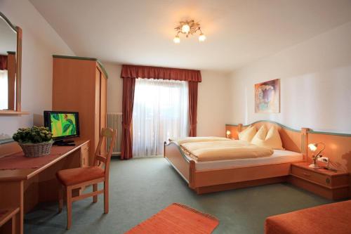 a bedroom with a bed and a desk and a computer at Pension Sonnblick in Westendorf