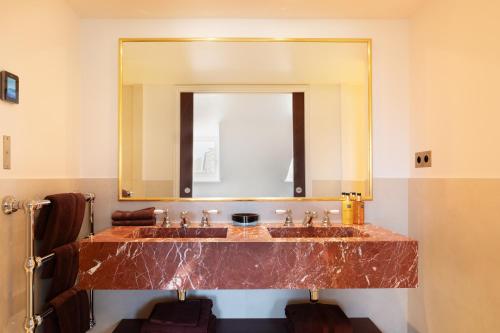 La salle de bains est pourvue d'un lavabo en marbre et d'un miroir. dans l'établissement ONIRI - Serviced Apartment in Ile de la Cité - Notre Dame, à Paris