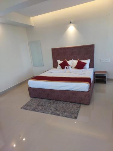 1 dormitorio con 1 cama grande con almohadas rojas en CAPITAL LODGE en Madikeri