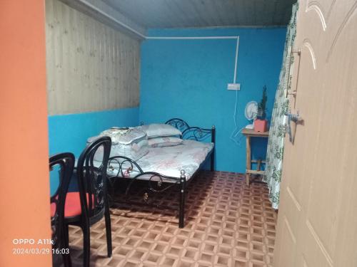 een kleine kamer met een bed en een blauwe muur bij Dsd Bomzon Homestay in Darjeeling