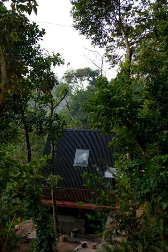 a house with a black roof and some trees at Aya natural in Ūdumbanshola
