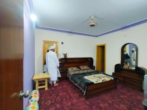 mężczyzna stojący w sypialni z łóżkiem w obiekcie Leepa Valley Guest House 