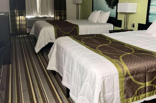 Percival的住宿－Super 8 by Wyndham Nebraska City，酒店客房带两张床,带白色和棕色的床单。