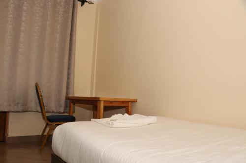 ein Schlafzimmer mit einem Bett, einem Stuhl und einem Tisch in der Unterkunft Motel Clavina in Gilgil