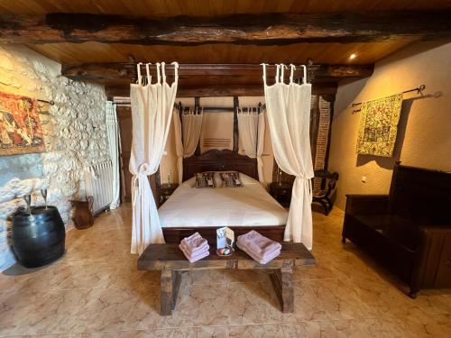 a bedroom with a bed with curtains and a table at Le Relais des Chevaliers "Suite des Seigneurs" in Cordes-sur-Ciel