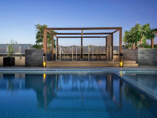een zwembad met een tuinhuisje op de achtergrond bij Pullman Dubai Creek City Centre in Dubai