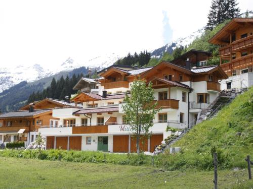 eine Gruppe von Gebäuden auf einem Hügel mit einem Baum in der Unterkunft Apartment in Saalbach-Hinterglemm with sauna in Saalbach-Hinterglemm