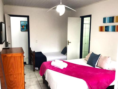 a bedroom with two beds and a dresser and a television at Suites Brothers Centro in Búzios