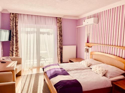 a bedroom with a bed with purple walls and a window at Villa Lux in Hévíz