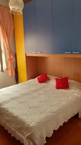 sypialnia z łóżkiem z 2 czerwonymi poduszkami w obiekcie Affittacamere Tortolì w mieście Tortolì