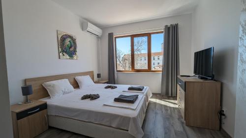 ein Hotelzimmer mit einem Bett und einem TV in der Unterkunft Apartment DEVA in Baltschik