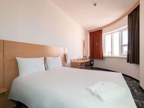 a bedroom with a large white bed and a window at Ibis Astana in Astana