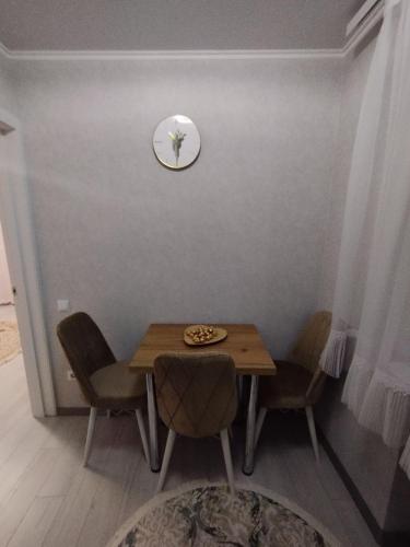 a dining room table with chairs and a clock on the wall at Balti Apartment in Bălţi