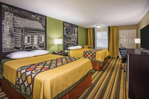 a hotel room with two beds and a desk at Super 8 by Wyndham Paragould in Paragould