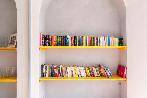 Um monte de livros em prateleiras amarelas. em Loft 33 em Piacenza