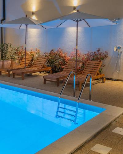a swimming pool with benches and umbrellas in a building at Goldberg Apartments Osijek in Osijek