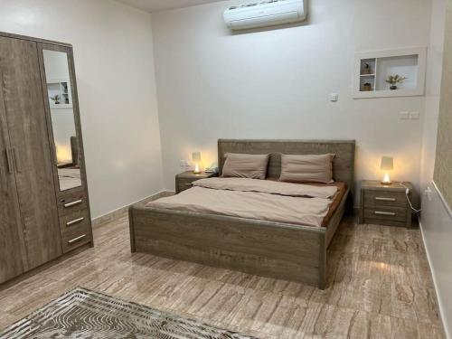 ein Schlafzimmer mit einem Bett mit zwei Nachttischen und einem Spiegel in der Unterkunft سكن تله الظاهره in Medina