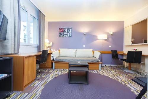 a living room with a couch and a desk at Aparthotel Chez Adagio Paris La Défense-2P with Terrace in Courbevoie