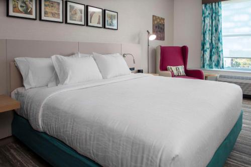 a bedroom with a large white bed and a red chair at Hilton Garden Inn Ocala Downtown, Fl in Ocala