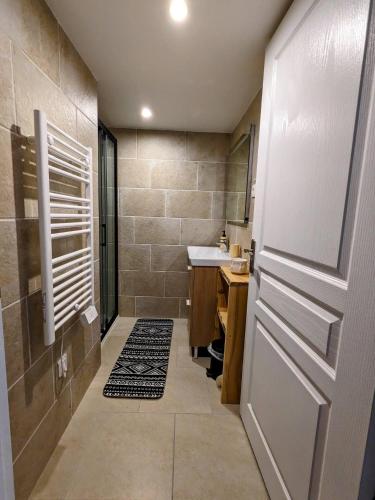 La salle de bains est pourvue d'une douche, d'un lavabo et d'une porte. dans l'établissement Le Tucou - Gîte & Spa Tout confort, à Campan