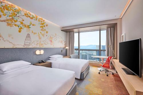 a hotel room with two beds and a flat screen tv at Hilton Garden Inn Suzhou Wuzhong in Suzhou