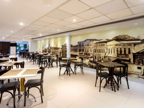 un restaurante con mesas y sillas y un mural de edificios en Ibis Styles Belém Hangar, en Belém