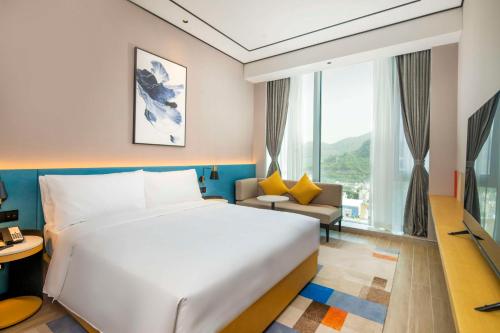 a hotel room with a bed and a large window at Hilton Garden Inn Shenzhen Airport,Enjoy 24-hour one way free delivery from hotel to Shenzhen Baoan Airport on the hour in Shenzhen