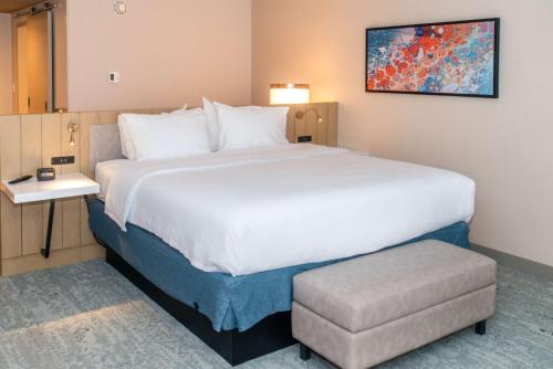 a hotel room with a large bed and a stool at Hilton Garden Inn Mattoon, IL in Mattoon
