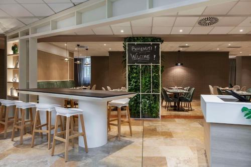 a restaurant with a bar and some chairs and tables at Hilton Garden Inn Bologna North in Bologna