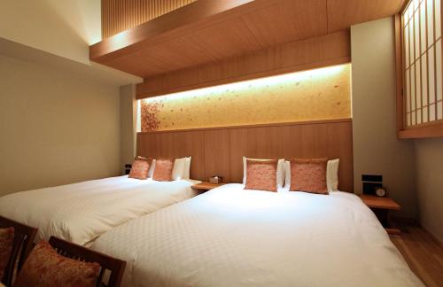 two beds in a hotel room with white sheets at KAYA Kyoto Nijo Castle, BW Signature Collection by Best Western in Kyoto