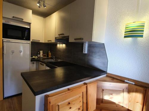 Il comprend une cuisine équipée d'un comptoir noir et d'un réfrigérateur. dans l'établissement Résidence Le Belvedere - Studio coin montagne au coeur des Orres 1650 MAE-6554, aux Orres