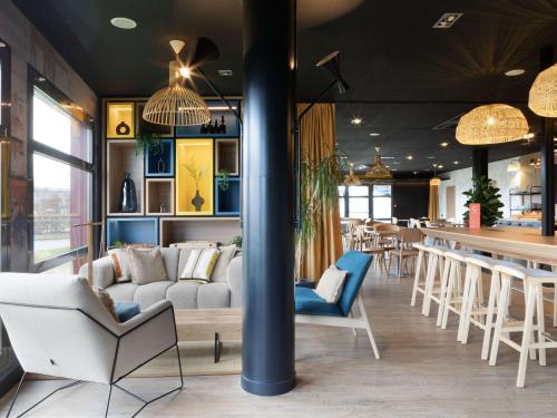 un restaurant avec un canapé, des chaises et un bar dans l'établissement ibis Douai Dechy, à Dechy