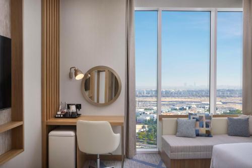 a bedroom with a desk and a mirror and a window at Hilton Garden Inn Dubai Business Bay in Dubai