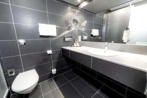 a bathroom with a toilet and a sink and a mirror at Mercure Bordeaux Lac in Bordeaux