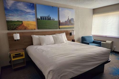 a bedroom with a large bed and a blue chair at Days Inn by Wyndham Davenport in Davenport