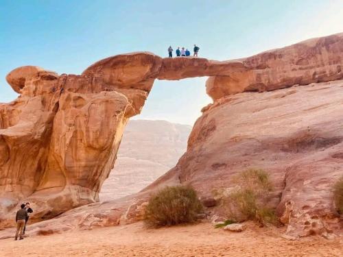 people standing on top of an arch in the desert at Tamim Luxury Camp in Wadi Rum