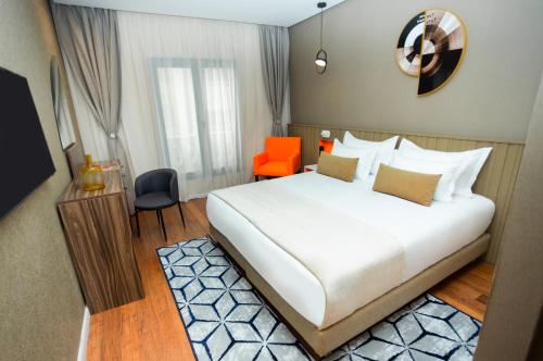 - une chambre avec un grand lit blanc et une chaise orange dans l'établissement Gray Hotel Casablanca, à Casablanca