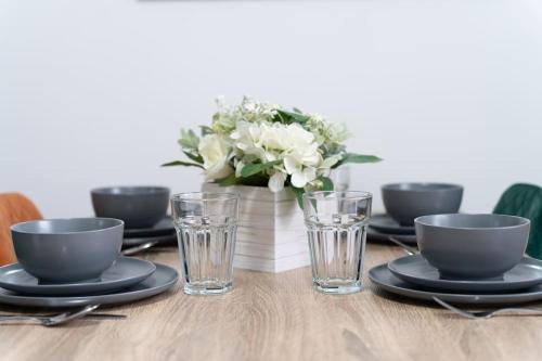 a table with plates and glasses and a vase of flowers at Open Mind Property - Luxury House & Free Parking in Portsmouth