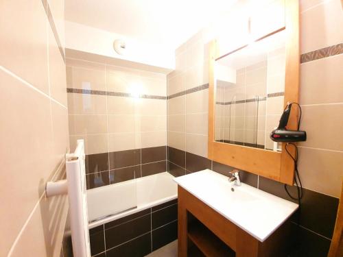 une salle de bain avec un lavabo, une baignoire et un miroir dans l'établissement Les Chalets Des Rennes - Appartement 2 pièces - Les Chalets Des Rennes MAE-9694, à Vars