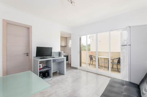 ein Wohnzimmer mit einem TV und einem Tisch mit Stühlen in der Unterkunft Acapulco Apartments in Can Picafort