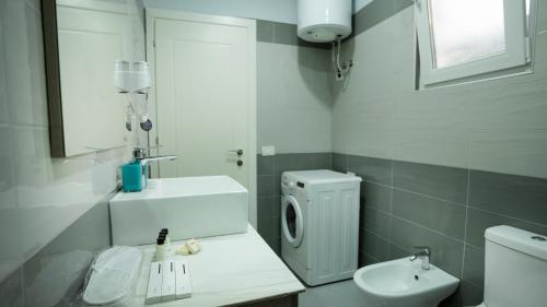 a white bathroom with a sink and a toilet at Gent's Inn in Durrës