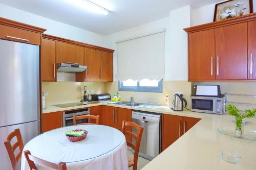 a kitchen with wooden cabinets and a white table with chairs at Villa Angelena in Droushia