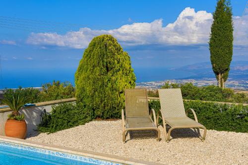 two chairs sitting next to a swimming pool at Villa Angelena in Droushia