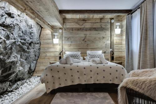 a bedroom with a bed and a stone wall at Résidence Cahokia - Chalets pour 13 Personnes 464 in Val-d'Isère
