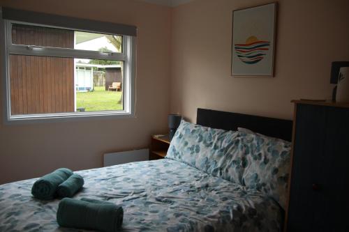 a bedroom with a bed and a window at Stonesthrow 184 Broadside Chalet Park Stalham in Stalham